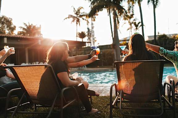 a group of people sitting around a swimming pool with drinks