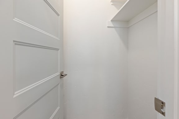 A white door with a silver handle is in a white room.