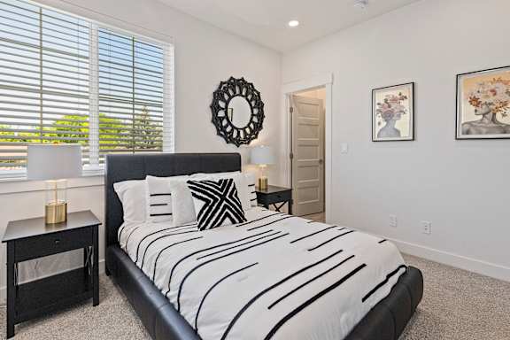 A bedroom with a black and white bedspread and a black headboard.