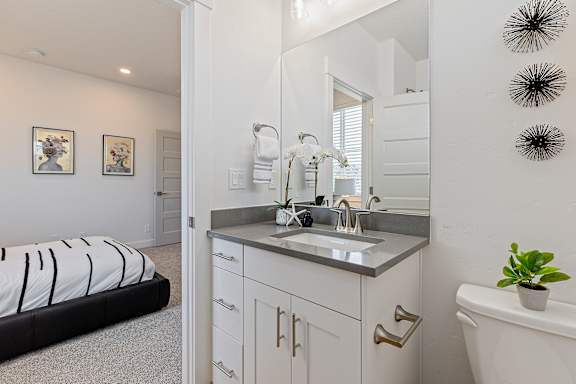 A bathroom with a white tub, sink, and a bed with a black and white striped comforter.