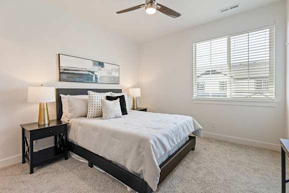 A bedroom with a bed, nightstand, and window.