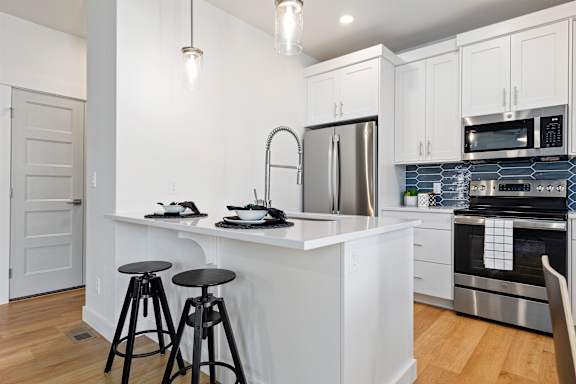 A kitchen with white cabinets and a white island with a sink.