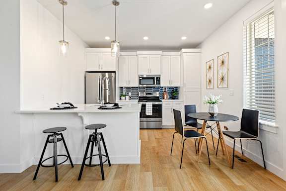 A kitchen with a white countertop and black bar stools.