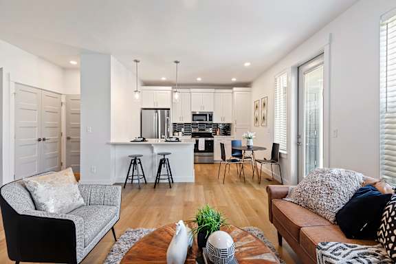 A modern living room with a kitchen in the background.