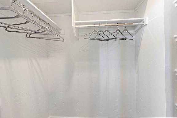 A white closet with clothes hangers.