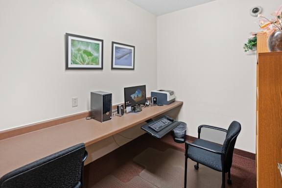 A room with a desk, two chairs, and a computer setup.