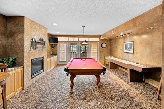 A room with a pool table and a fireplace.