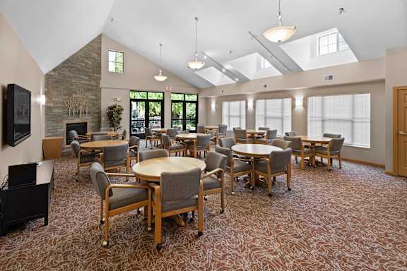 A room with tables and chairs and a stone wall.