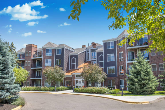 an exterior view of an apartment building with trees and a driveway