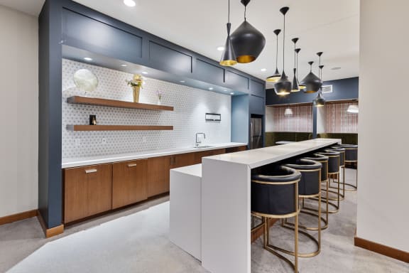 a communal kitchen with bar stools and blue and white tiles