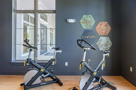 Two exercise bikes are in a room with a window.