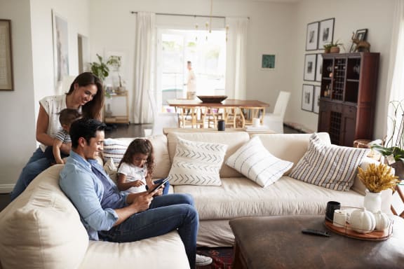a family sitting on a couch in a living room looking at a tablet
