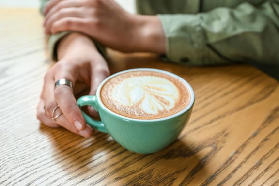 a person sitting at a table with a cup of coffee