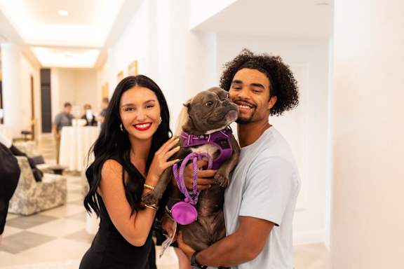 A man and woman holding a dog in a hallway.