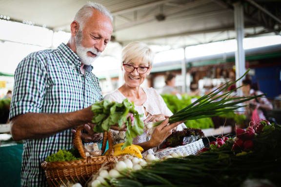 an older couple buying vegetables at a market