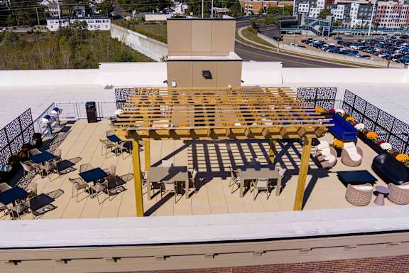A rooftop patio with a long table and chairs.