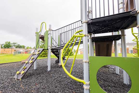 A playground with a yellow slide and a green play structure.
