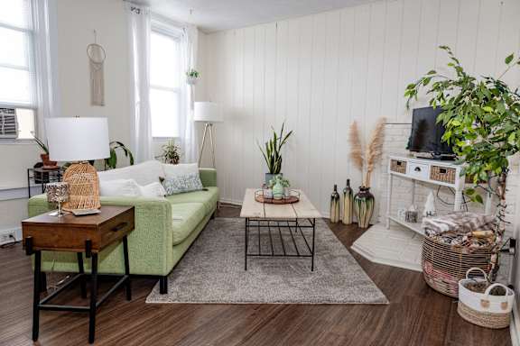 A living room with a green couch, a wooden table, and a white cabinet.