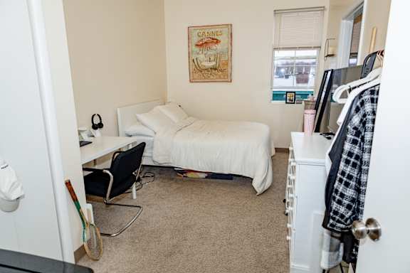 A bedroom with a bed, chair, and a poster on the wall.