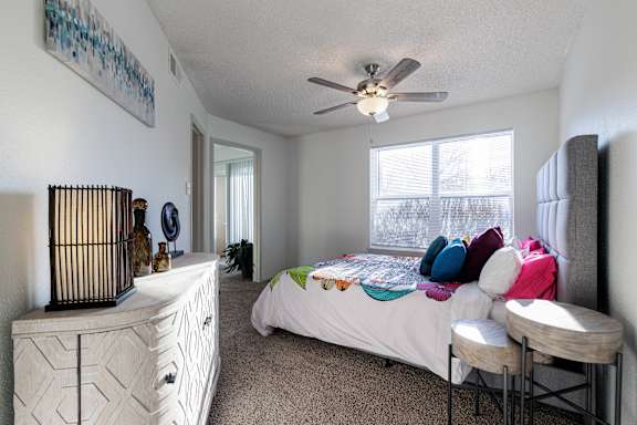The bedroom in the model unit at Skyler Ridge Apartments, featuring a bed and ceiling fan.
