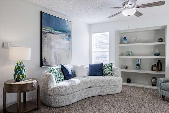 A spacious living room in the model unit of Skyler Ridge Apartments, with a comfortable couch and ceiling fan.