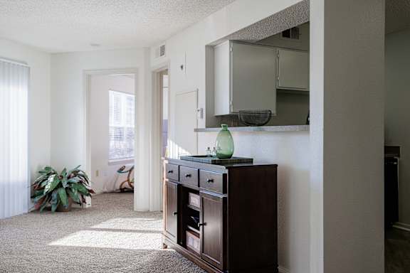 A view of the living room in the model unit at Skyler Ridge Apartments, with a dresser and a mirror on the wall.