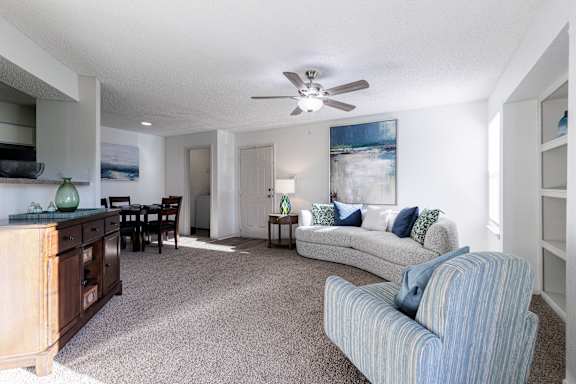 Lounge area in the model unit at Skyler Ridge Apartments, with a couch and ceiling fan.