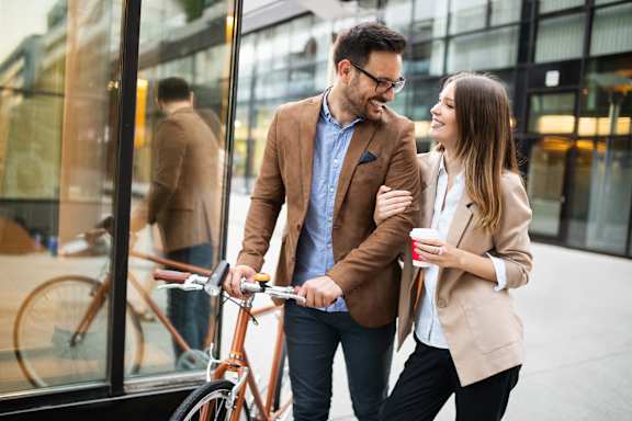 a man and a woman walking a bike down the street