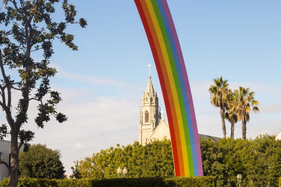 a rainbow sculpture in front of a church