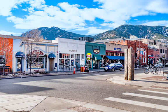 A street view of a town with shops and a mountain in the background.