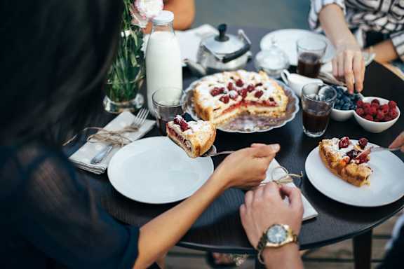 a group of people sitting around a table eating cake