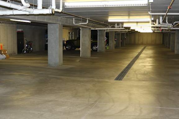 A parking garage with concrete pillars and a concrete floor.
