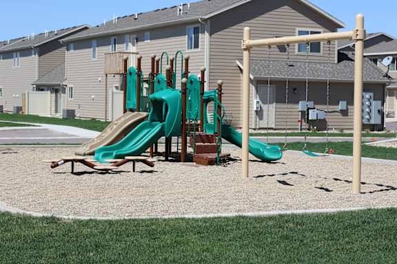 A playground with a green slide and a wooden structure.