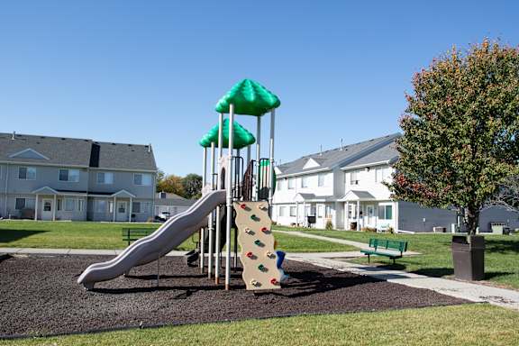A playground with a green slide and a climbing wall.