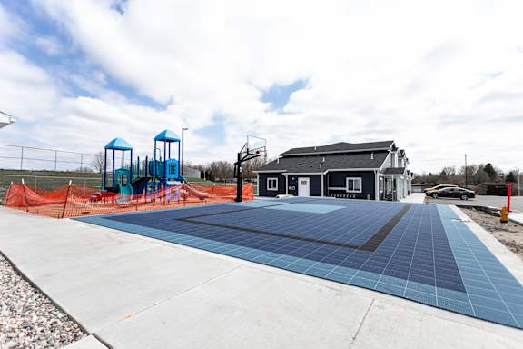 A playground with a blue slide and a building in the background.