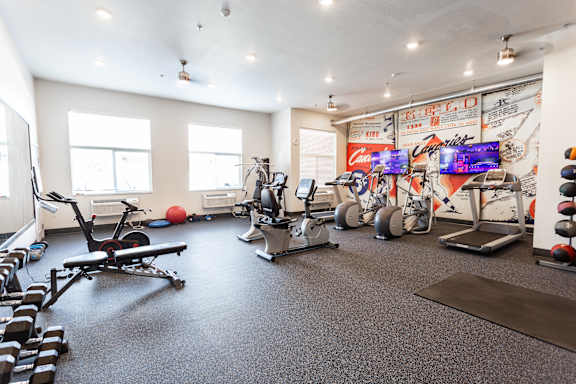 A gym with a variety of equipment including treadmills, weights, and exercise machines.