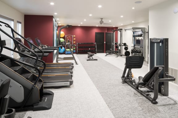 a gym with treadmills and other exercise equipment in a room with red walls