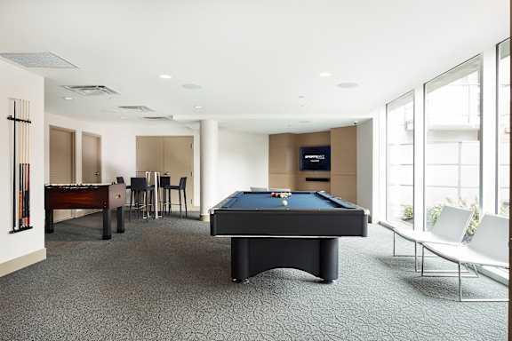 A pool table is in the middle of a room with a piano and a TV.