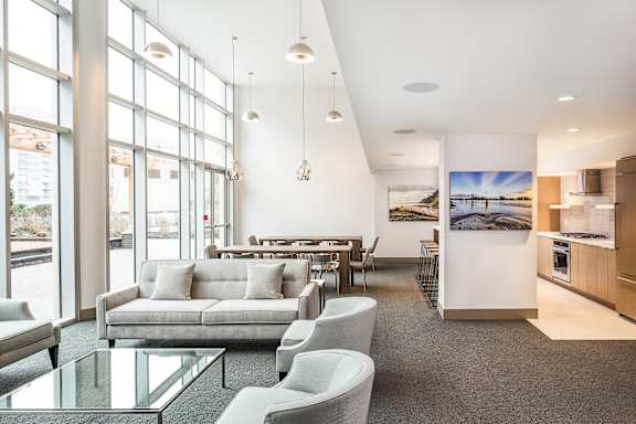 A modern living room with a kitchen area in the background.