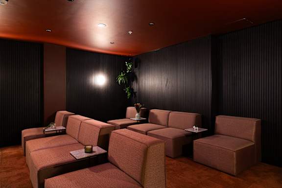 A room with a dark background and a brown sofa.