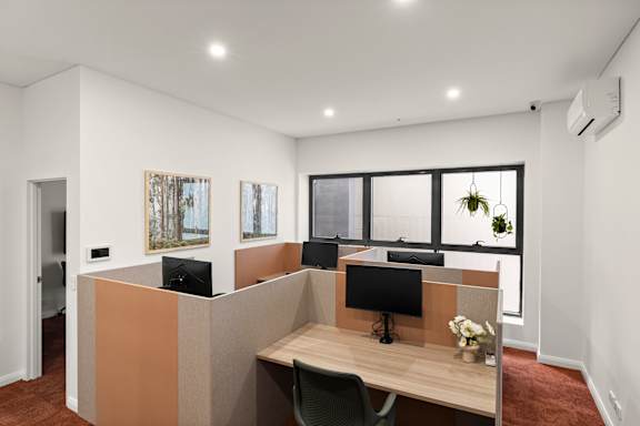 A modern office space with a wooden desk and two computer monitors.