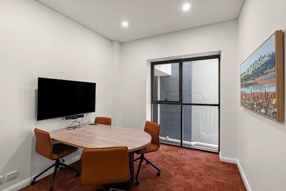 A conference room with a table, chairs and a television.