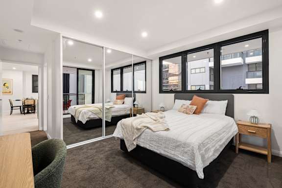 A bedroom with a large bed and a chair.