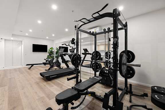 A gym with a variety of equipment including a treadmill, weights, and a bench press.