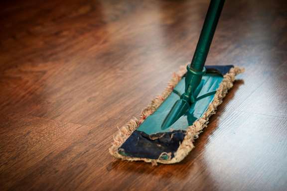 A mop is cleaning a wooden floor.