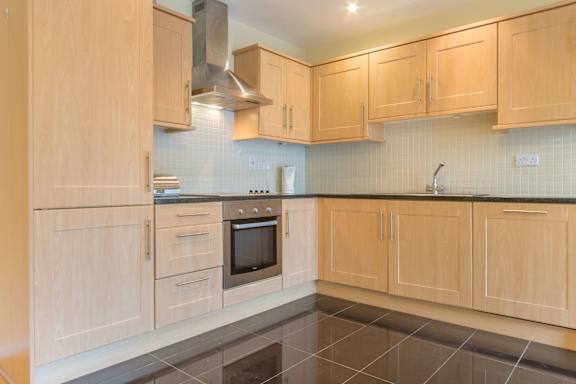 a large kitchen with wooden cabinets and a black tiled floor