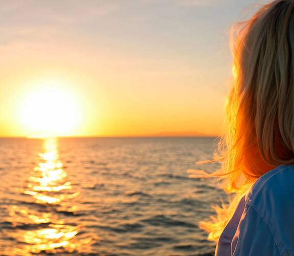 two women watching the sunset over the ocean