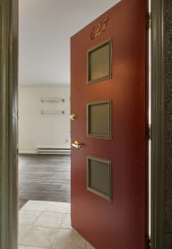 an open red door leading into a room with a hall way and a white floor