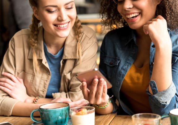 two women sitting at a table looking at a cell phone at The Bohen Apartments, Minnesota, 55408