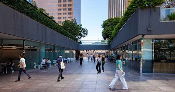 People walking in a courtyard with greenery on the walls.